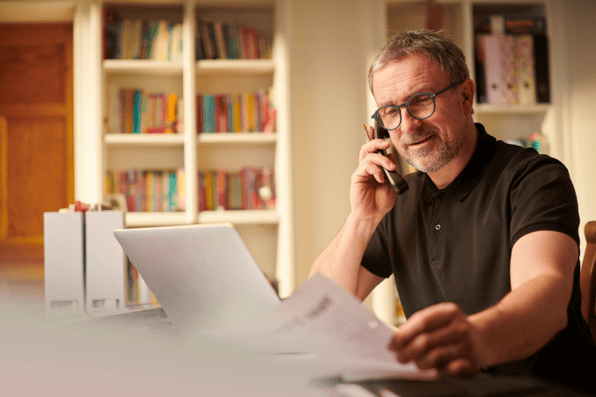 A business owner looking at documents showing cashflow challenges that have caused his business to go into debt