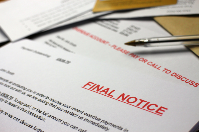 The words Final Notice on legal Debt collection letters on a table alongside a black pen outlining the legal debt collection process for someone who owes a debt.  