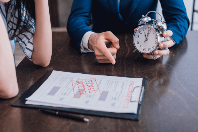 A man holding an alarm clock, showing a woman a debt recovery letter that is due, saying final notice that a creditor has written themselves to the debtor.  